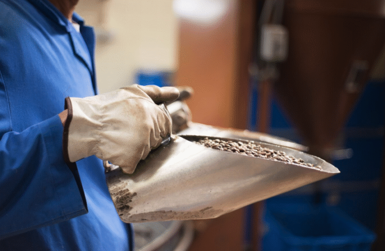 a person holding a metal scoop with coffee beans